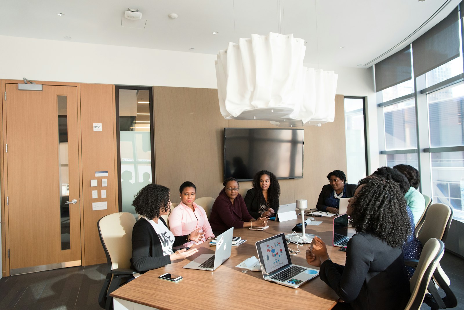 Black women professionals collaborating around a boardroom table with laptops